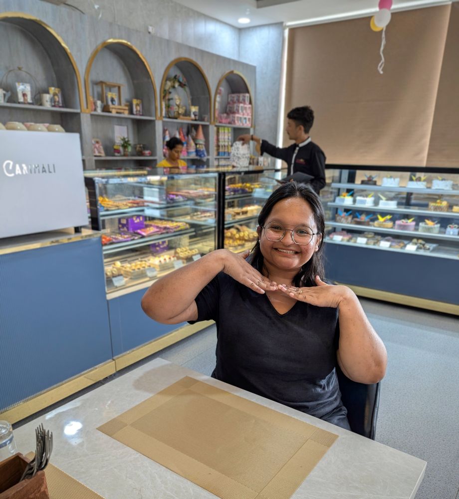 Me sitting in a bakery with a big smile on my face