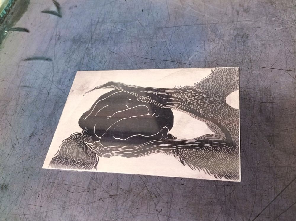 A picture of a zinc plate, etched with intaglio techniques. It represents a naked figure in a fetal position, face obscured, gently pressed in the beak of a giant bird.