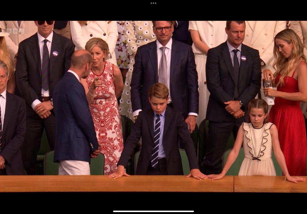 A screenshot of the royal box at the men's Wimbledon final, including Prince George standing with his hands on the barrier, looking stern.