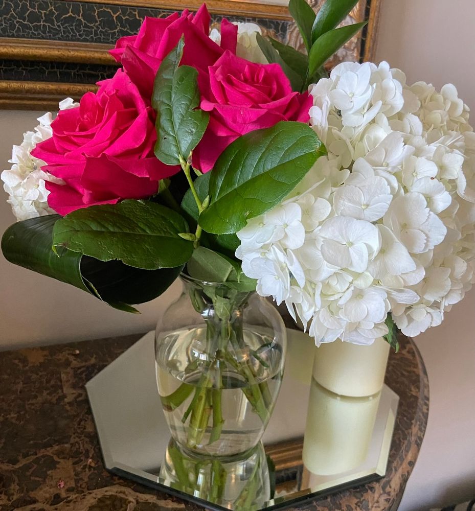 A vase with red roses and white hydrangeas. 