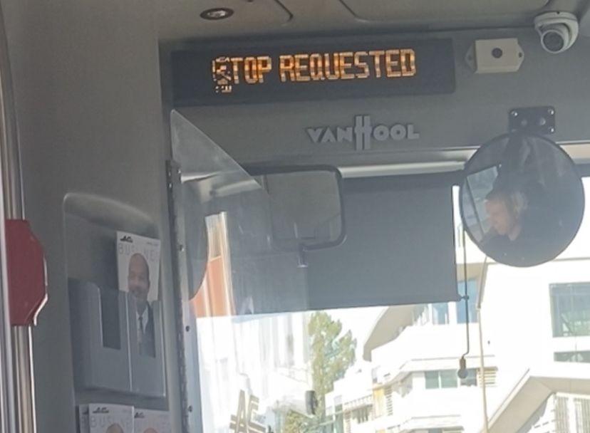An AC Transit Van Hool bus aboard Route 52 with the Stop Requested sign active, though the first S is corrupted, reading "Top Requested" instead