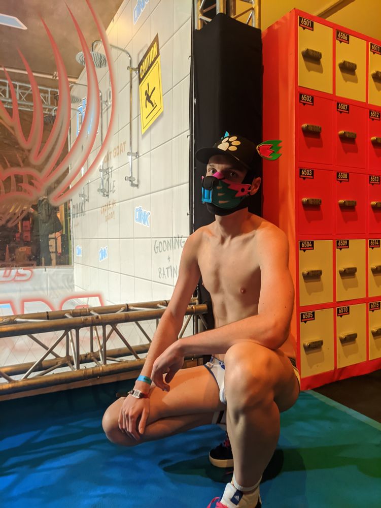 A puppy sitting in front of showers and locker boxes.