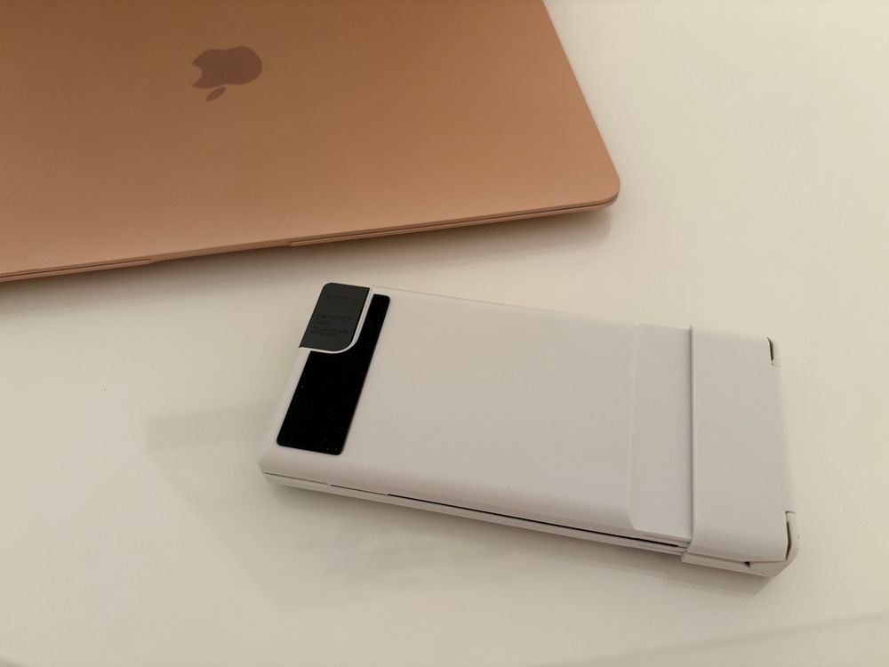 A white Korg nanoKEY Fold MIDI controller folded shut next to a Macbook Air.