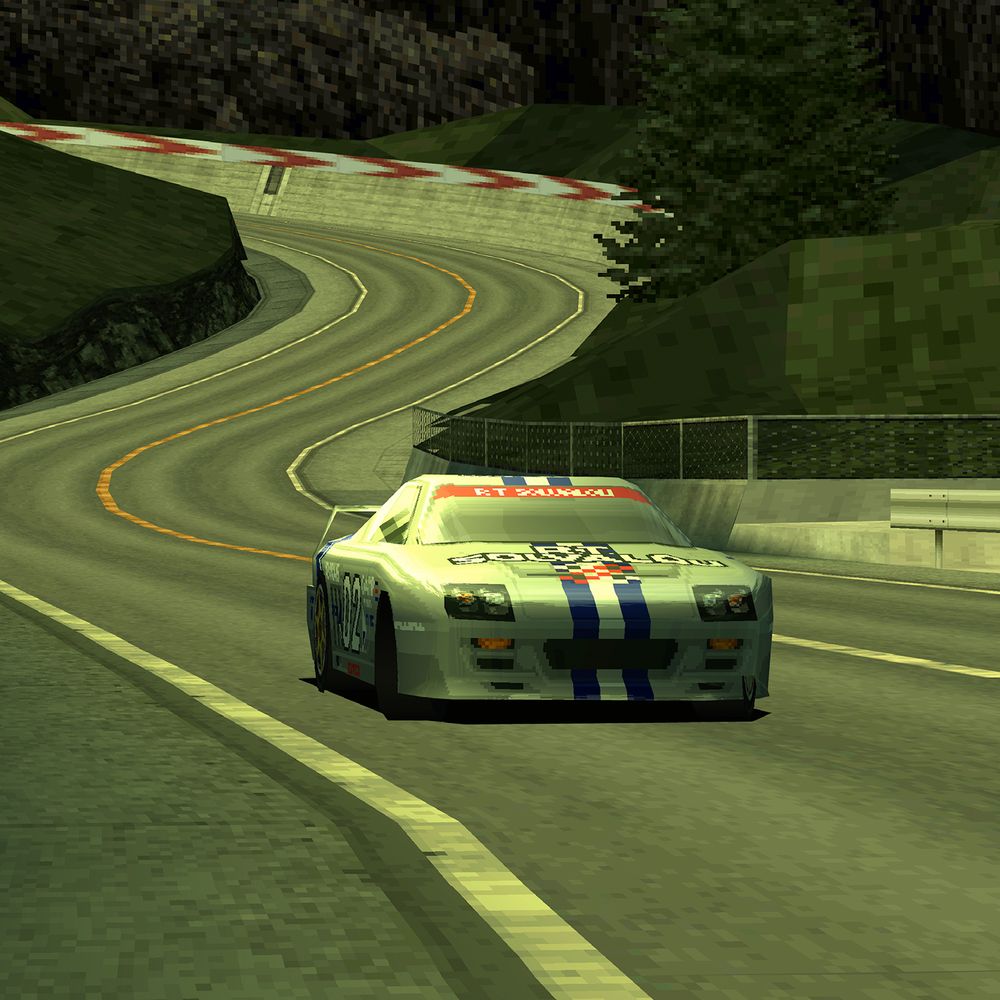 A car drives along a winding track at sunset.