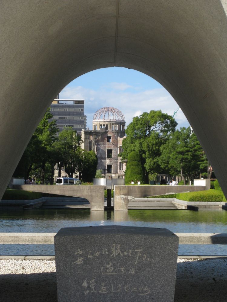 The A-Bomb Dome and Peace Flame seen through the Hiroshima Memorial Cenotaph.