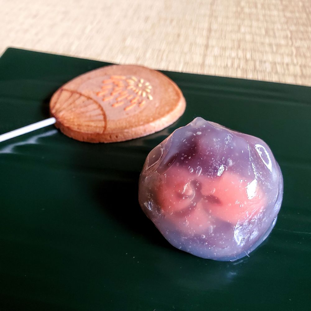 Sweets for the Gozan-no-Okuribi. A jellied confection features a red and purple yokan imprinted with the shape of Daimonji. Beside it is a biscuit in the shape of a fan with an iced fireworks design.