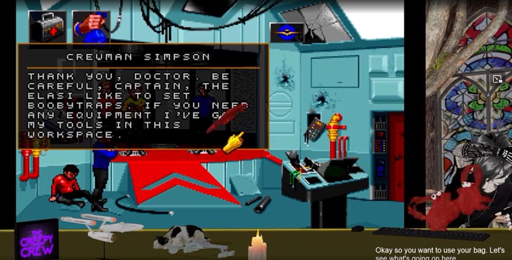 A scene from CtrlAltMinuit's stream.  They are playing "Star Trek - 25th Anniversary", there is a cat sitting on the desk between two models of spaceships, and are ducking because for some reason crabs with googly eye are flying through the air at them.