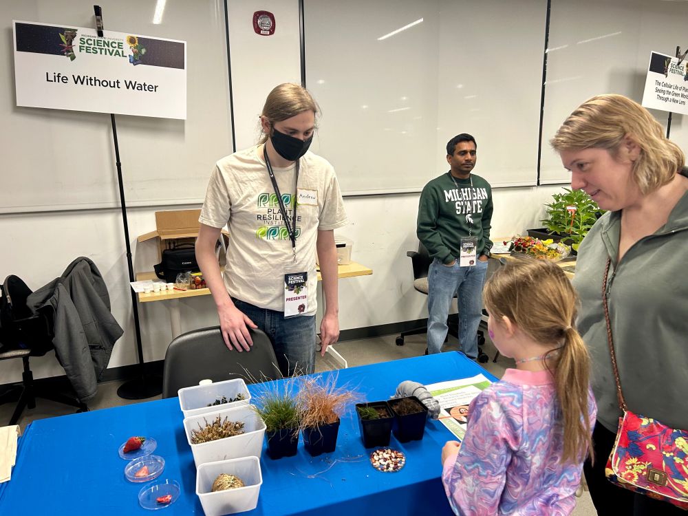 Two participants in the "Life Without Water" booth listen to a presenter explain how tardigrades can survive dehydration.