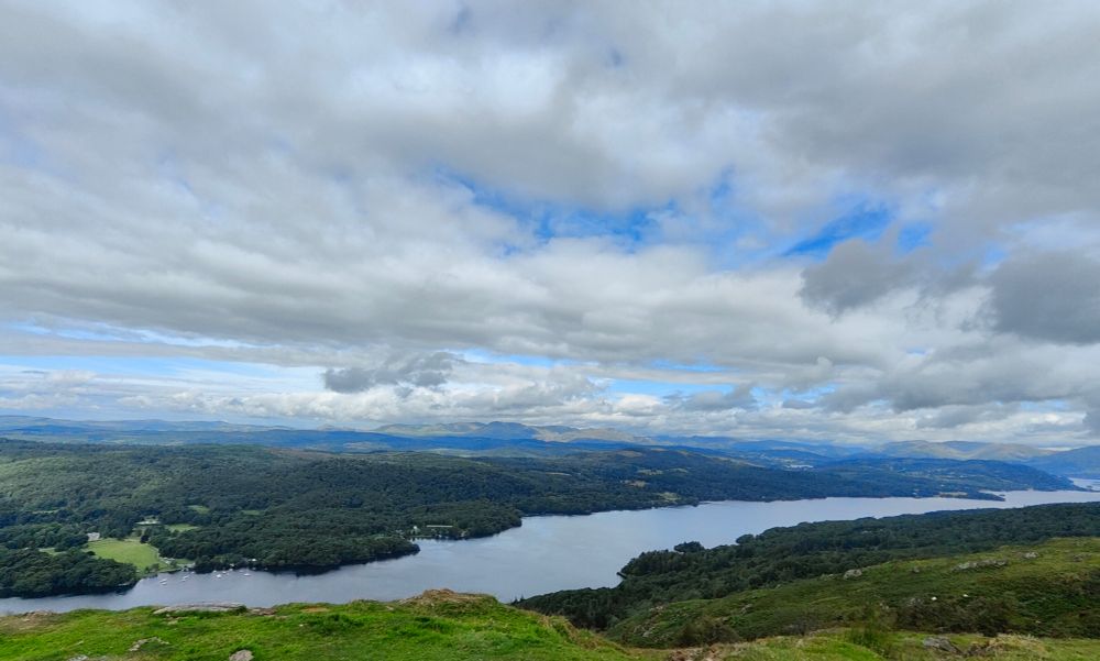 A view of Windermere and countless hills beyond. Above, clouds mix with blue sky and it all feels kind of limitless 