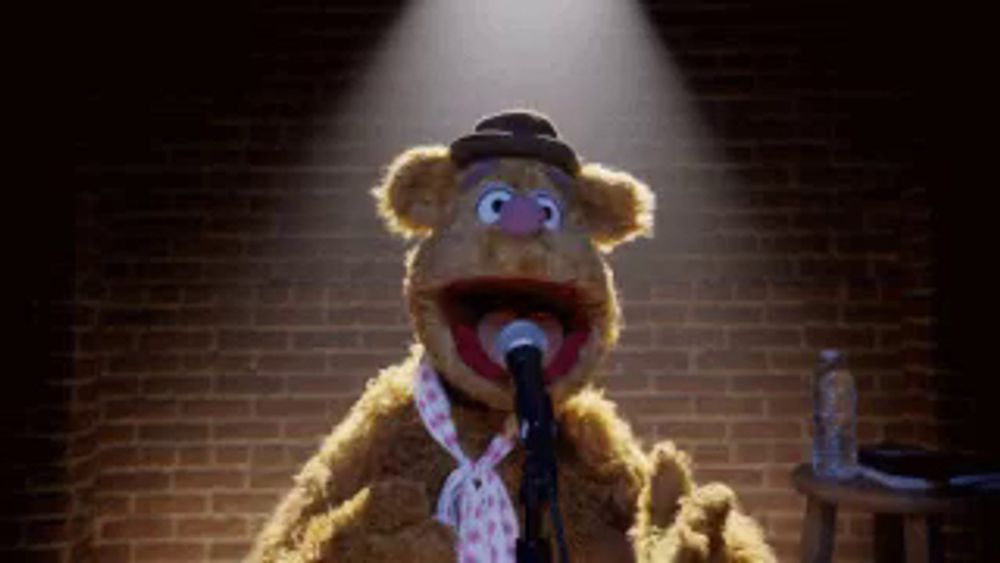 a teddy bear is singing into a microphone while wearing a tie .