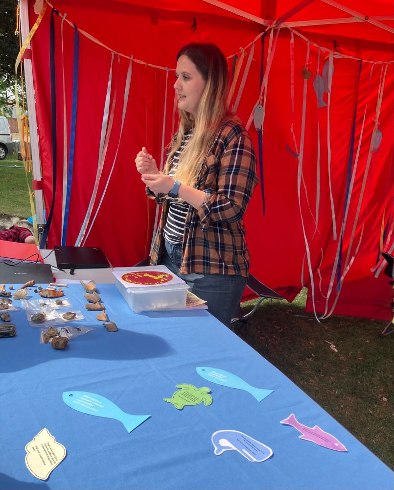 Grace,  of the  Coasts in Mind team, standing behind a table with finds from the beach at Whitstable. 