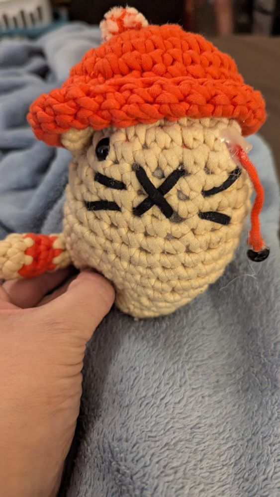 Crochet cat with eye dangling out of the socket. 
