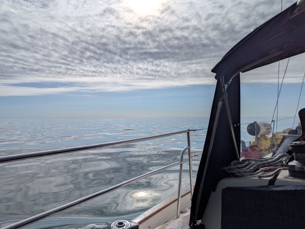 A photo from our sailboat of the calm seas which are grey and fade into the grey, cloudy sky. 