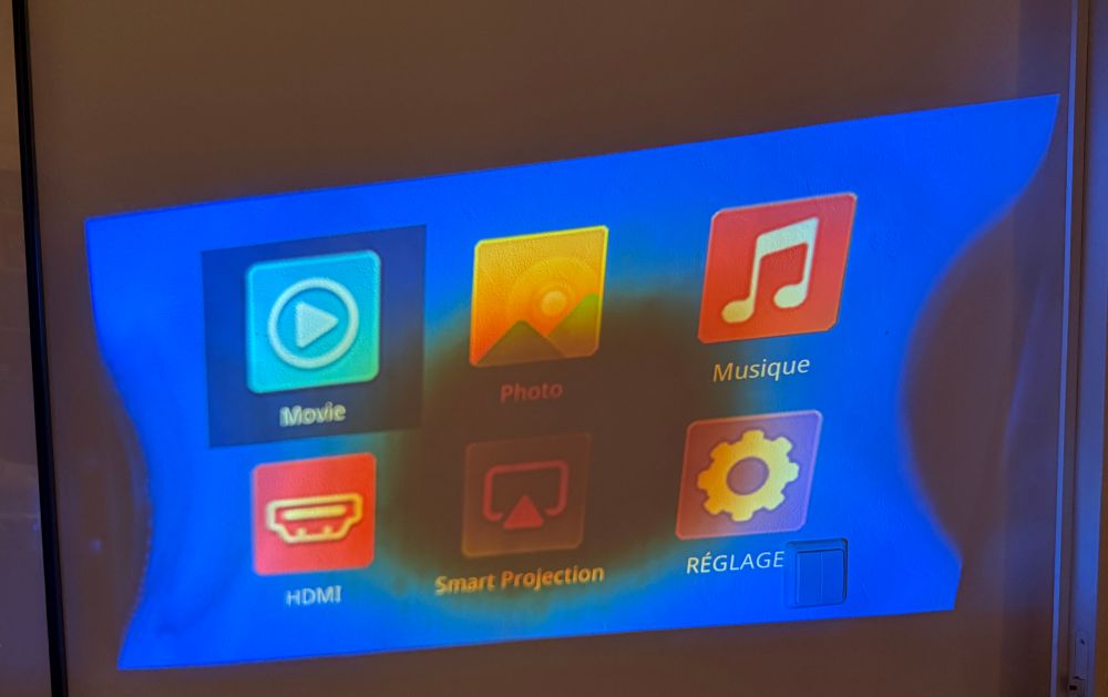 Projector image on a wall showing the OS start screen with wobbly sides and dark spot in the middle