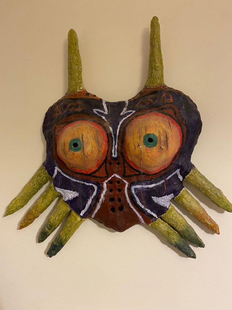 A battered old Majora's Mask made of weathered wood and plaster.