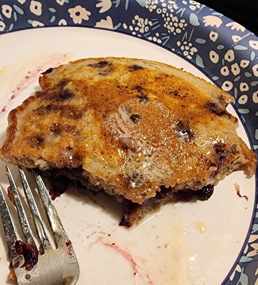 Blueberry pancake on a paper plate with a fork. 
