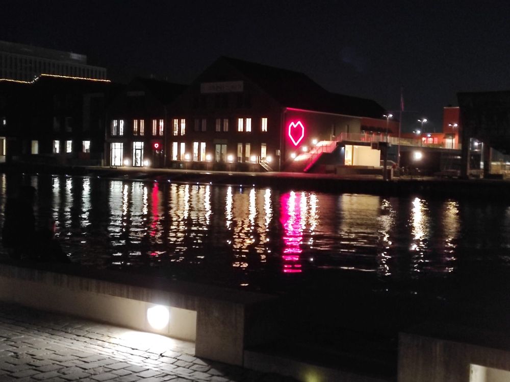 Innenhafen im Dunklen. Ein lila Herz spiegelt sich im Wasser 