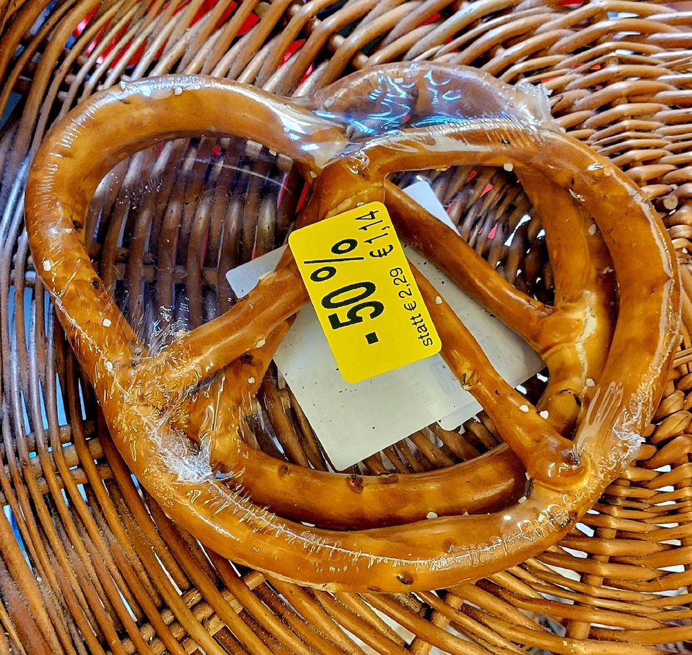 Two large thin pretzels in a wicker basket. The pretzels are wrapped in clear plastic and are stacked somewhat vertically.

Yellow sticker on package with black text: 50%