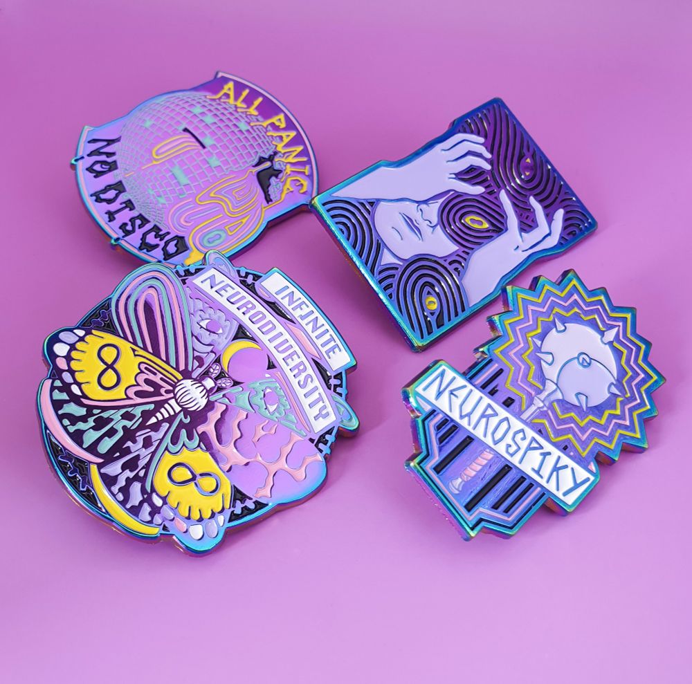 A photo of four rainbow plated enamel pins on a purple background. They include: an 8 winged moth with a banner reading 'infinite neurodiversity', a mace with a spiky aura and a banner reading 'neurospiky', a cracked disco ball with shapes leaking out and drippy typography reading 'all panic no disco', and a pin version of the previous illustration representing Overwhelm, with the shapes in black.