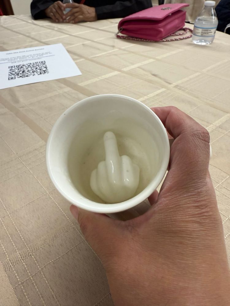 A cup with a hand flipping off someone who drinks it.