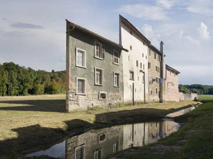 The facade of a bunch of buildings located on a creek, just a single wall nothing behind it