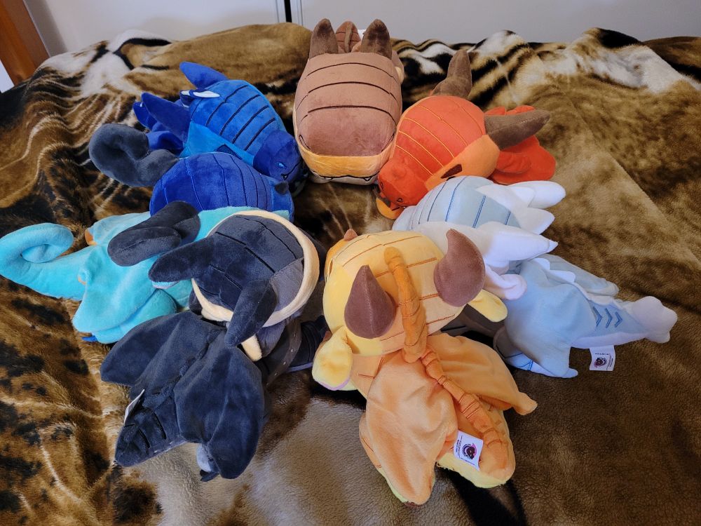 Photo of all 7 plushies sitting in a circle facing each other.