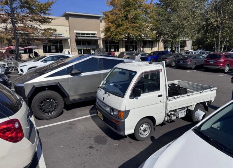 a small kei truck beside a cybertruck 