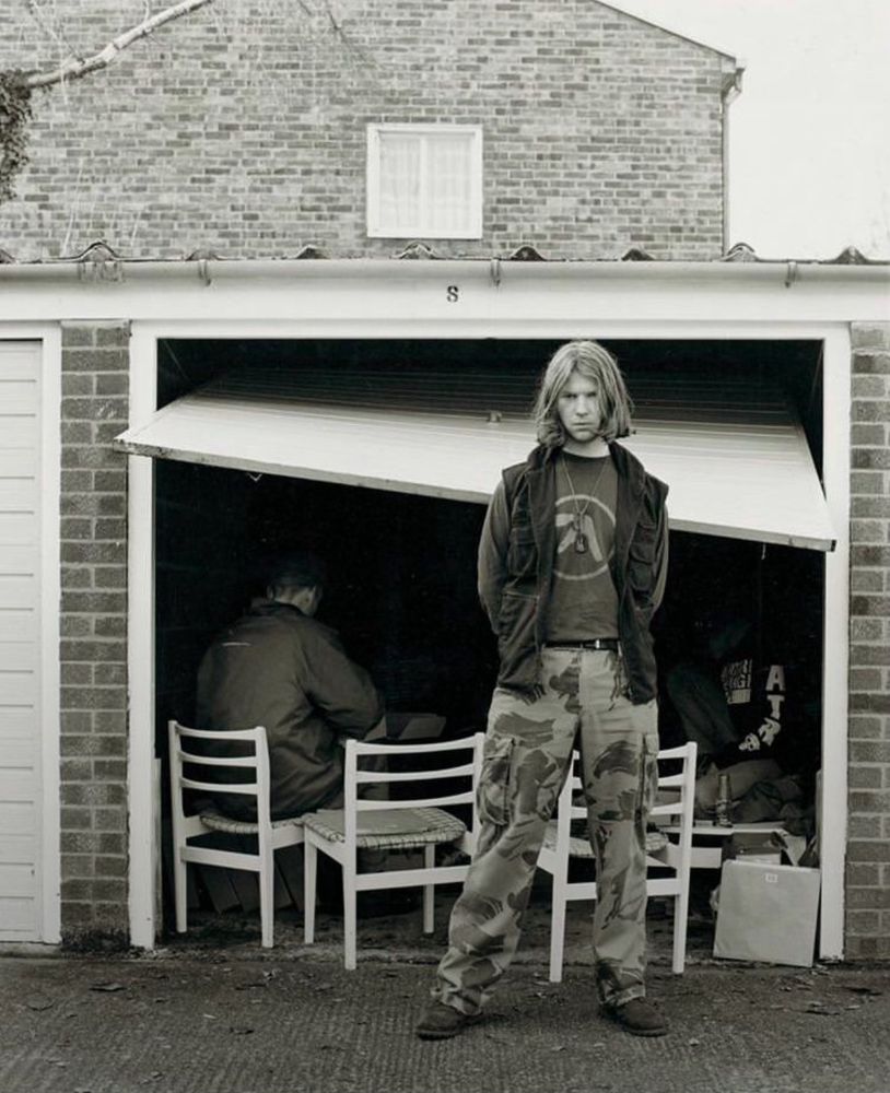 Richard standing in front of a broken garage door where people are gathered inside 