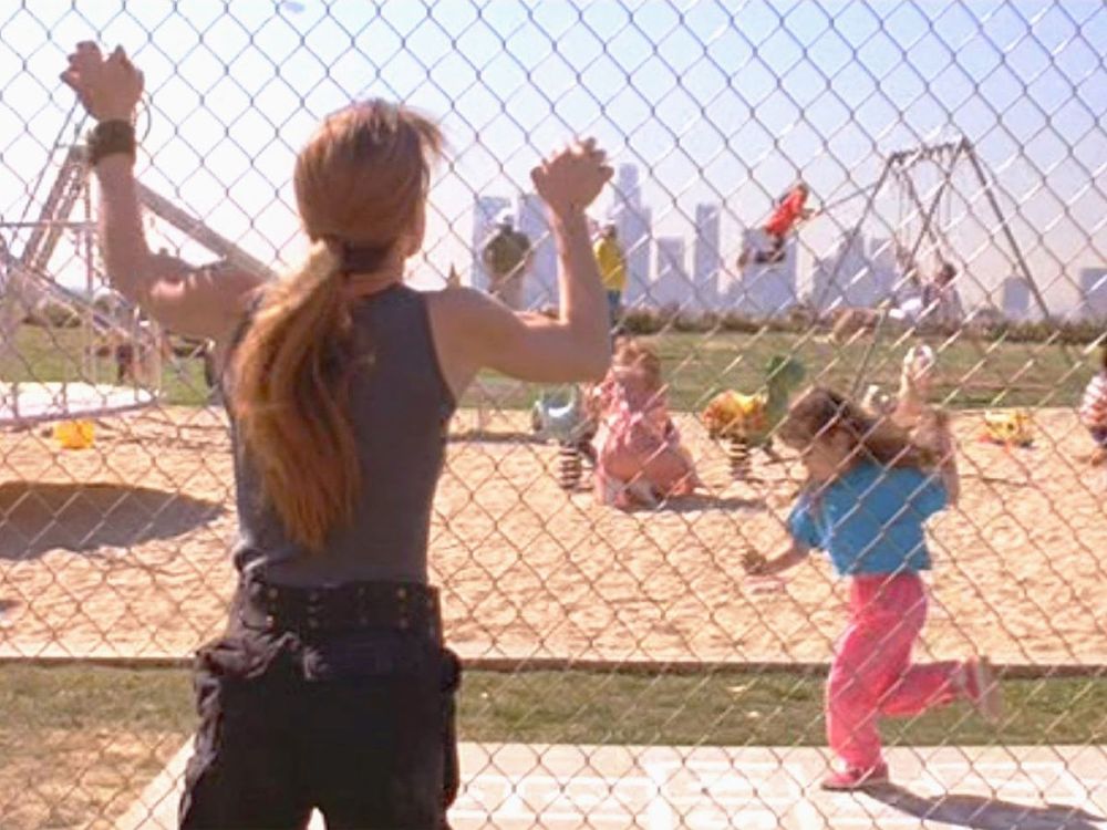 Sarah Connor, shouting wordlessly, grips a playground fence trying to warn the children of her nightmare 