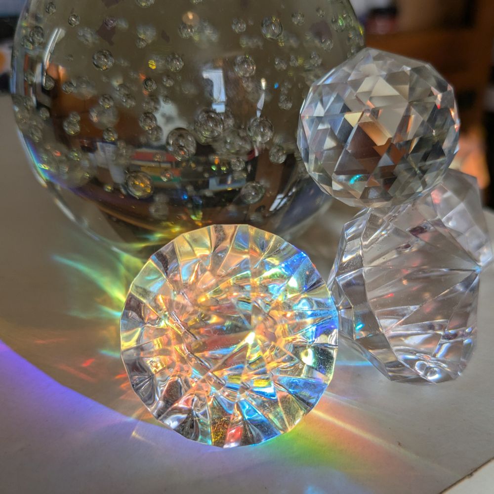 Lots of cheap gewgaws, the nearest of which is being lit by a beam of rainbow sunlight split from a triangular prism.