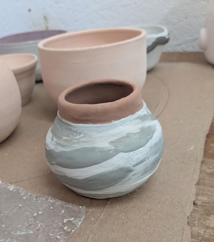 A small pot with swirls of different color glaze that  is matte