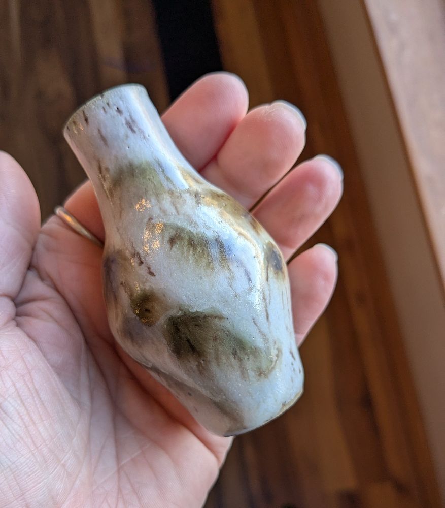 A small vase that fits in the palm of a hand.