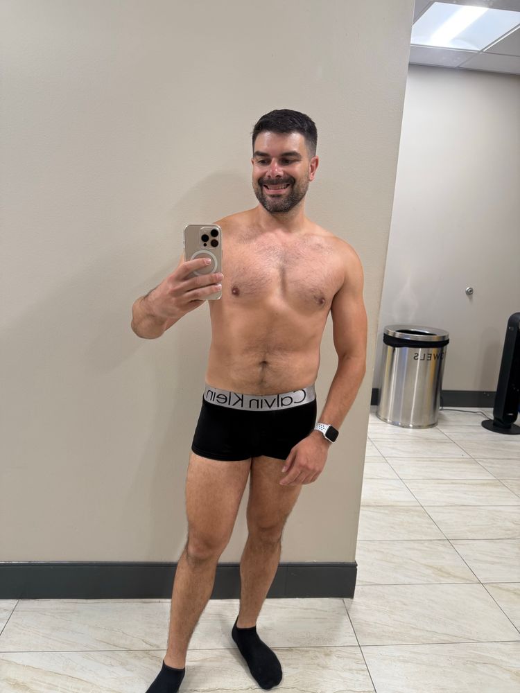 Man in underwear, taking a mirror selfie in the locker room