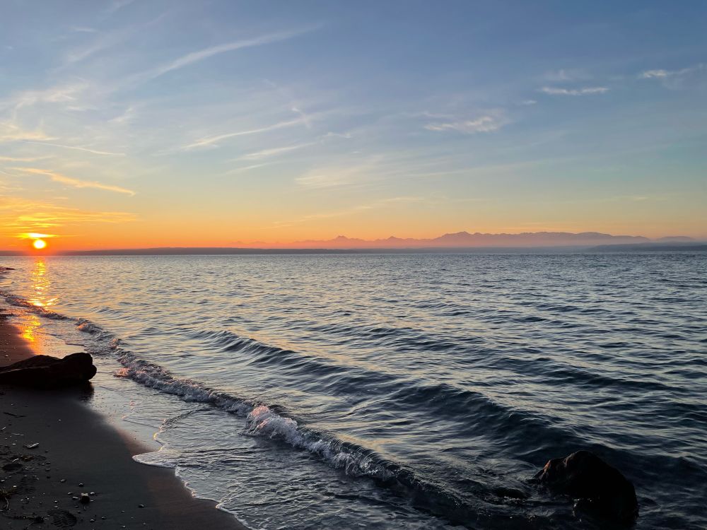 Sunsets over the water of the puget sound with Olympic mountain range in the distance