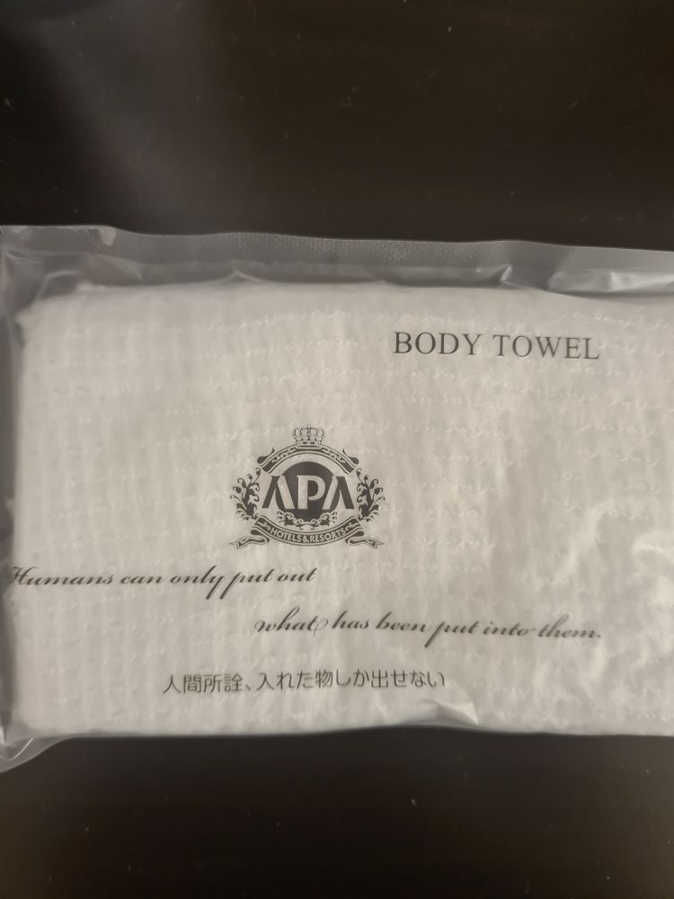 White body towel in plastic packaging with black text