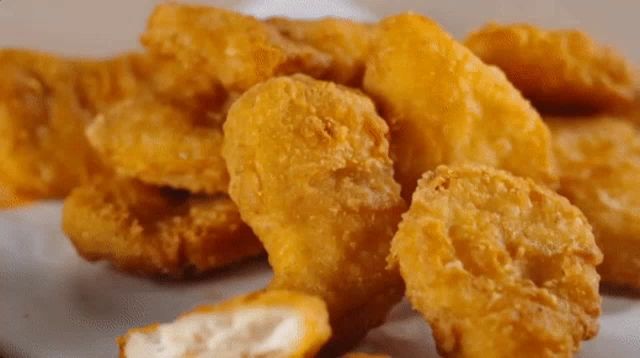 a close up of a pile of chicken nuggets with a bite taken out of one