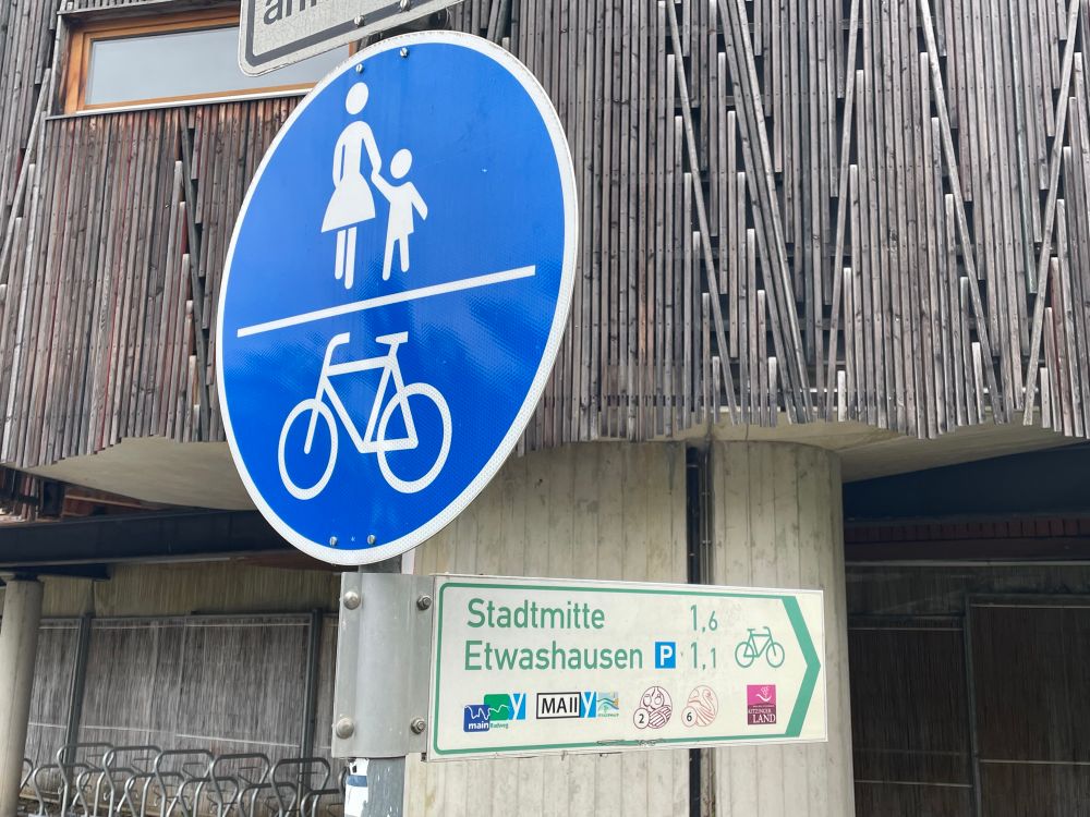 Traffic sign for bike riders .. showing one name of a small town named „Etwashausen“, which sounds like „SomethingTown“. 