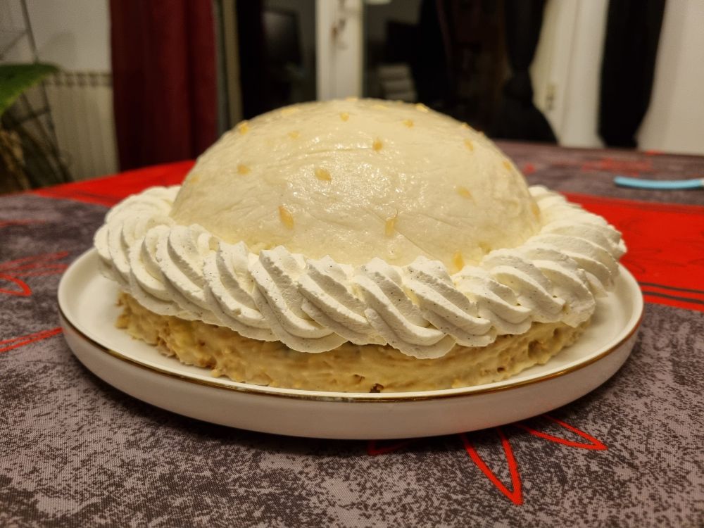 Gâteau composé d'un dôme blanc, entouré à sa base d'un pochage de chantilly, le tout sur une base de biscuit.