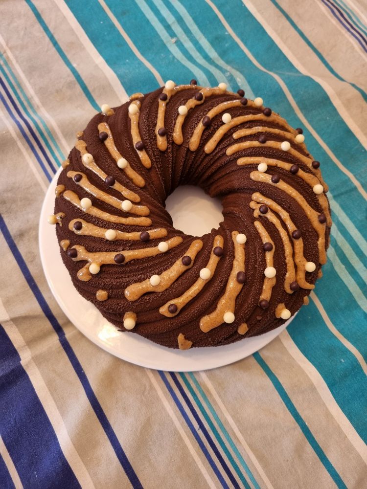 Entremet en couronne decoré avec des filets de praliné et billes croustillantes