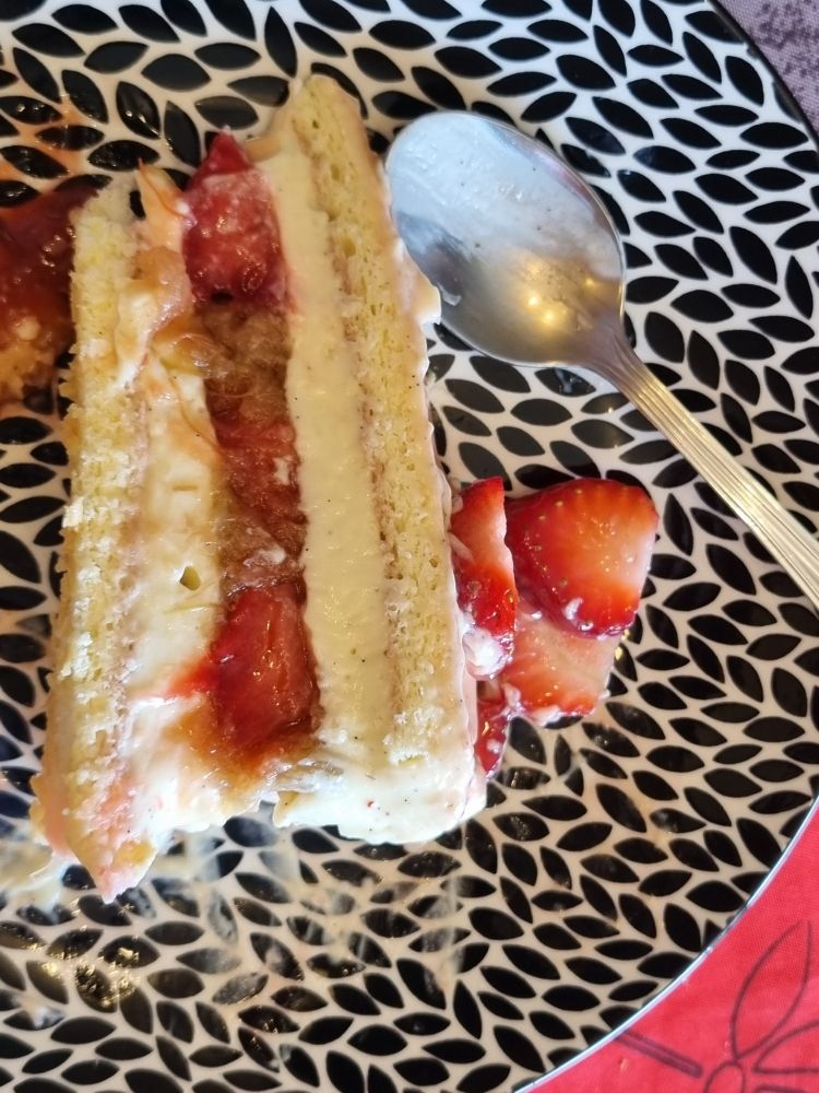 Découpe du gâteau : un insert de compotée de rhubarbe et morceaux de fraises, encadré par une crème diplomate, encadré par du biscuit cuillère.