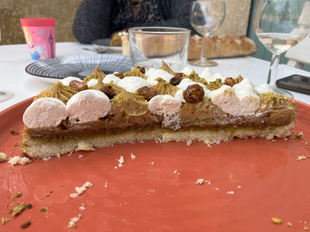 Découpe de la tarte : pâte sucrée, crème de pistache, praliné pistache, cremeux pistache, diplomate pistache , chantilly fleur d'oranger et pistache caramélisées.