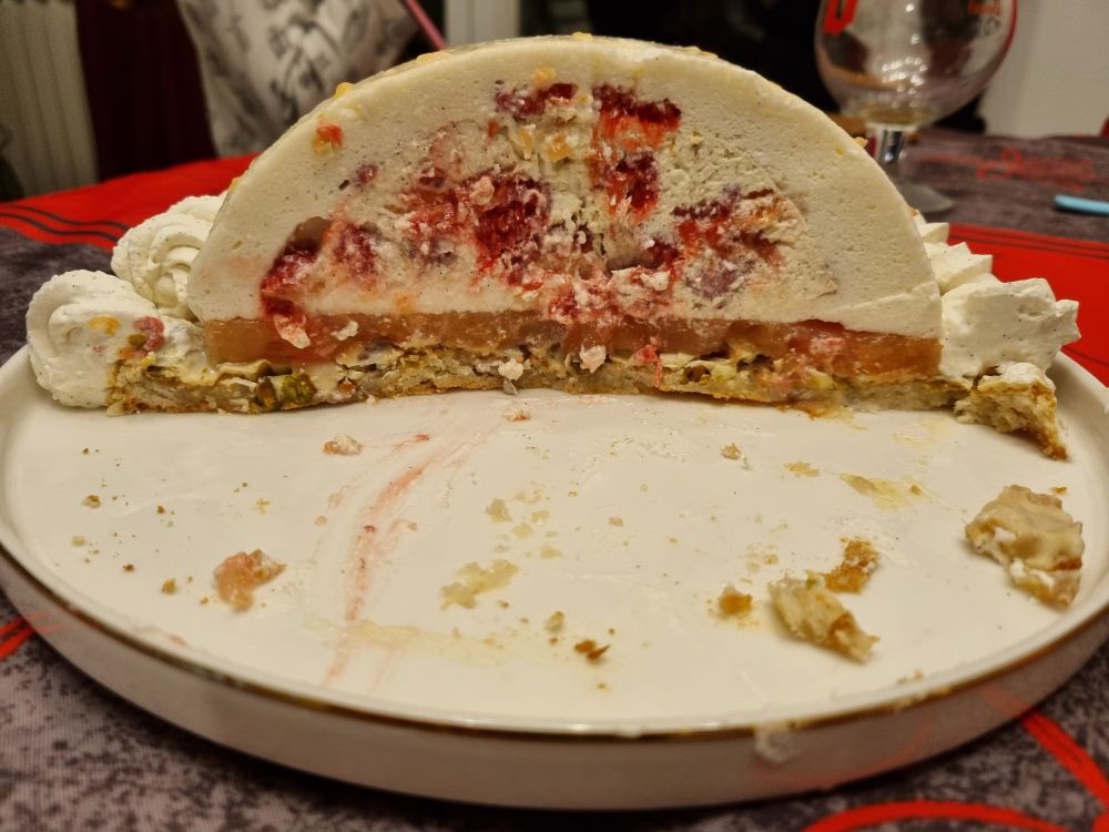Découpe du gâteau. La couche extérieure du dôme est une mousse litchi, à l'intérieur un dôme vanille avec des morceaux de pamplemousse et des  framboises. Entre le dôme et le biscuit on voit un insert au pamplemousse.