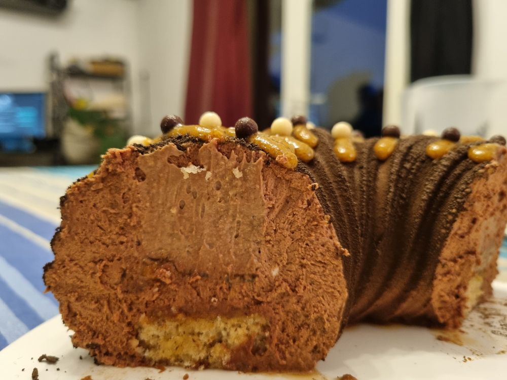 Découpe de l'entremet, ronde, avec le financier en bas, l'insert au chocolat entouré de la mousse chocolat noisette.