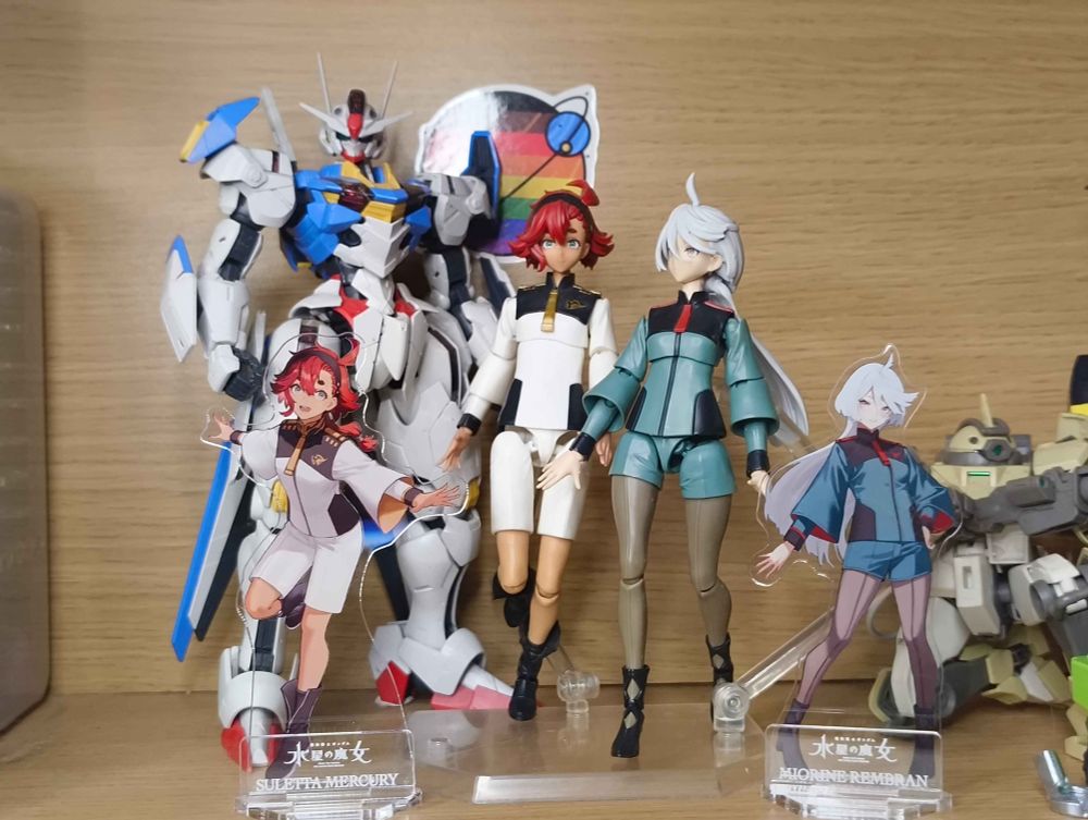 A display consisting of (from front to back):
1/100 Full Mechanics Gundam Aerial
Figure Rise Standard Suletta Mercury and Miorine Rembran posed as if walking together.
Acrylic standees for Suletta Mercury and Miorine Rembran.
HG 1/144 Chuchu's Demi Trainer is crouched slightly off screen.
