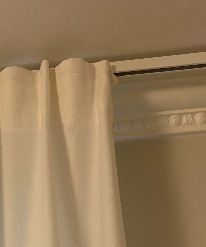 Bild på en vit gardin i en takskena