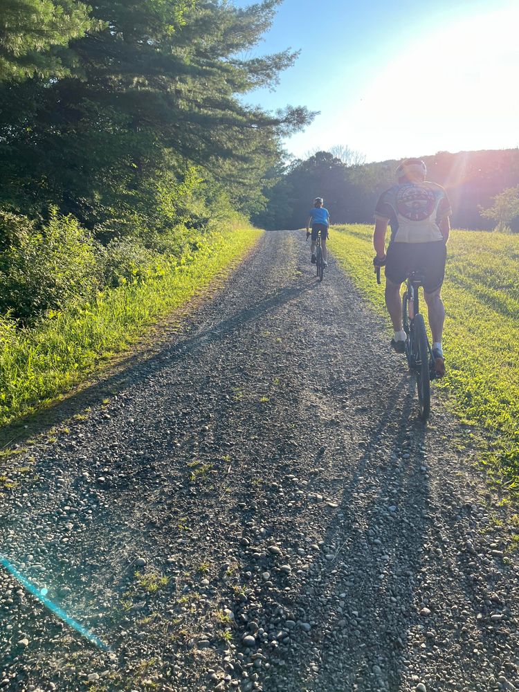 Two bikers riding on gravel, straight into the sun.