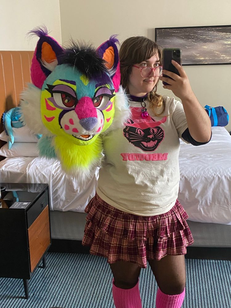 a gay person holding a sparklecat fursuit mirror selfie