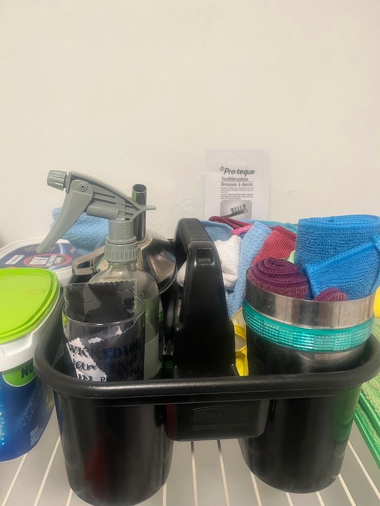 Pictured is a cleaning caddy with cleaning toothbrushes, microfiber cloths, a funnel, and one spray bottle with homemade multi surface cleaner
