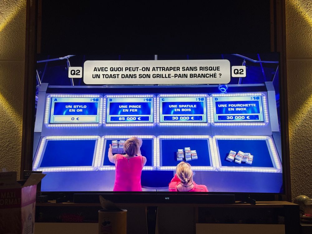 Photo de l’émission « Money Drop » les candidates doivent choisir une réponse à la question « avec quoi peut-on attraper sans risque un toast dans son grille-pain branché? » 
Elles misent sur « une pince en fer » 90k € 
Sur « une spatule en bois » 30k € 
Sur « une fourchette en inox » 30k € 
0€ sur la réponse « un stylo en or » 
