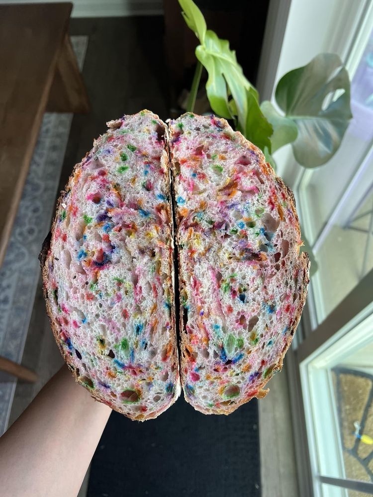 rainbow funfetti sourdough bread cut in half exposing the speckled rainbow center